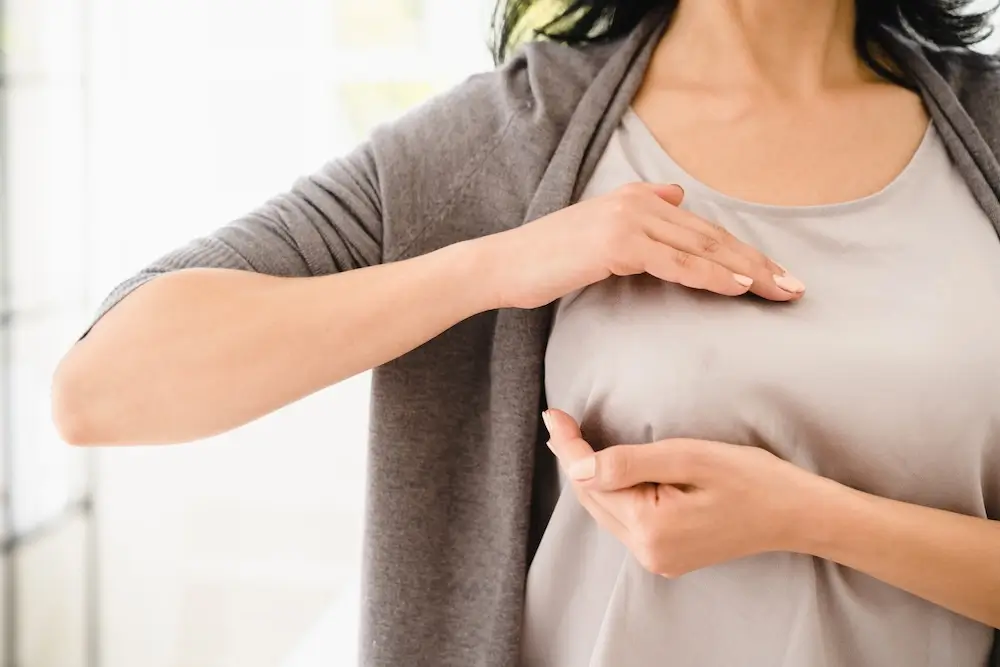 Woman performing a breast self-exam by feeling her breast.